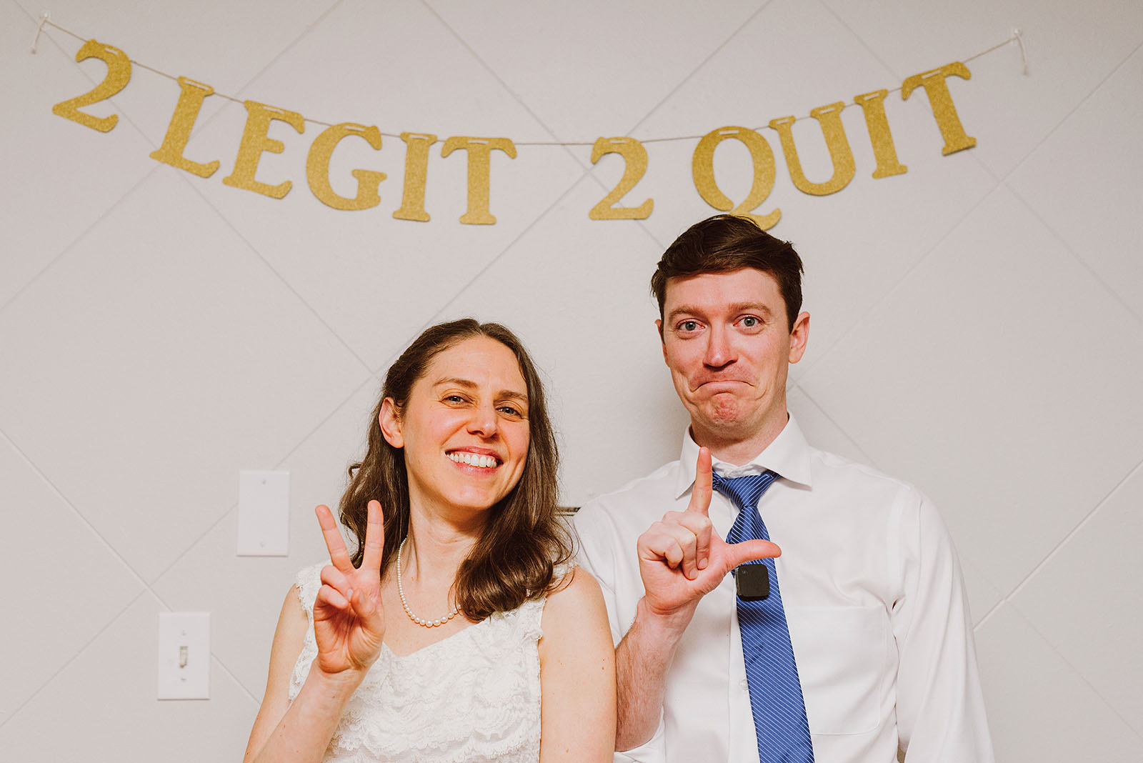 Bride and Groom in front of their homemade 2 Legit 2 Quit banner