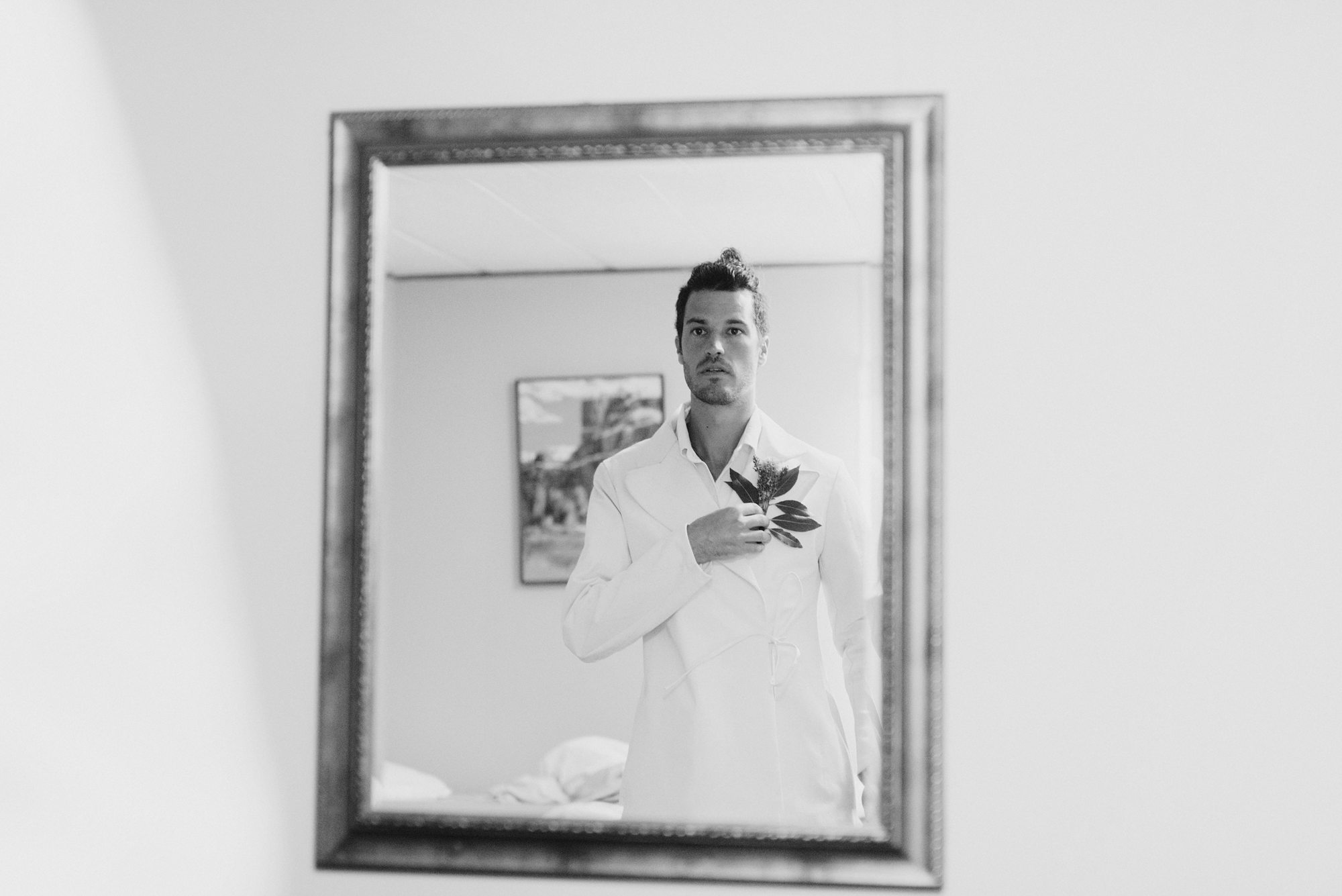 Groom attaching his boutonniere while looking in the mirror | Portland Wedding Photographer